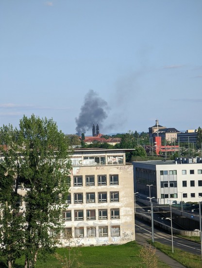Dunkle Rauchschwaden zu sehen, davor Gebäude